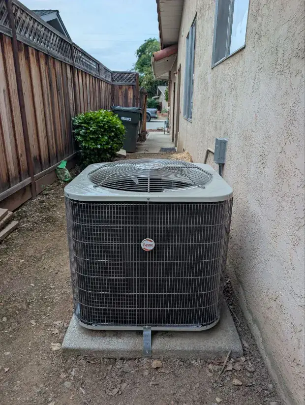 Payne air-conditioning condenser Sunny installed on a pad beside the house
