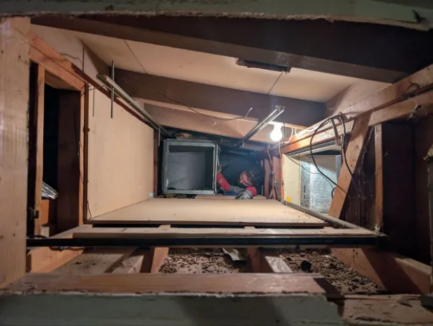 Sunny technician fitting a duct boot in a crawl space under the floor