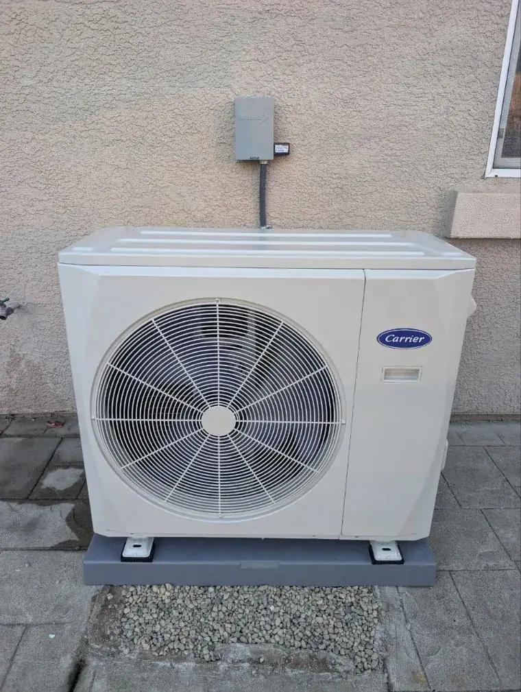 Carrier heat pump Sunny installed on a plinth beside a Bay Area home, disconnect fitted above it
