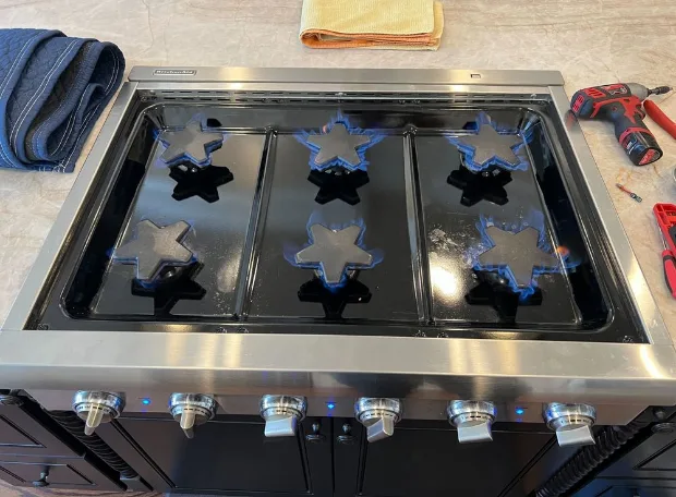 Six-burner gas rangetop lit across every burner after a Sunny repair